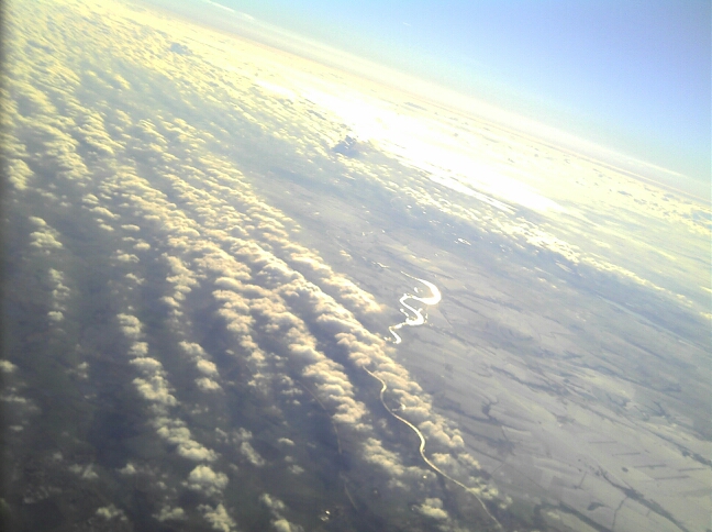 Felder, Wolken und ein Fluss aus großer Höhe
